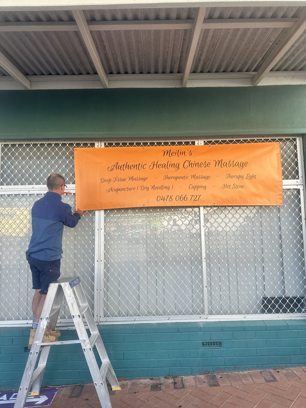 The Kneaded Relief shopfront on Rockingham Beach Road, with a banner going up on the window